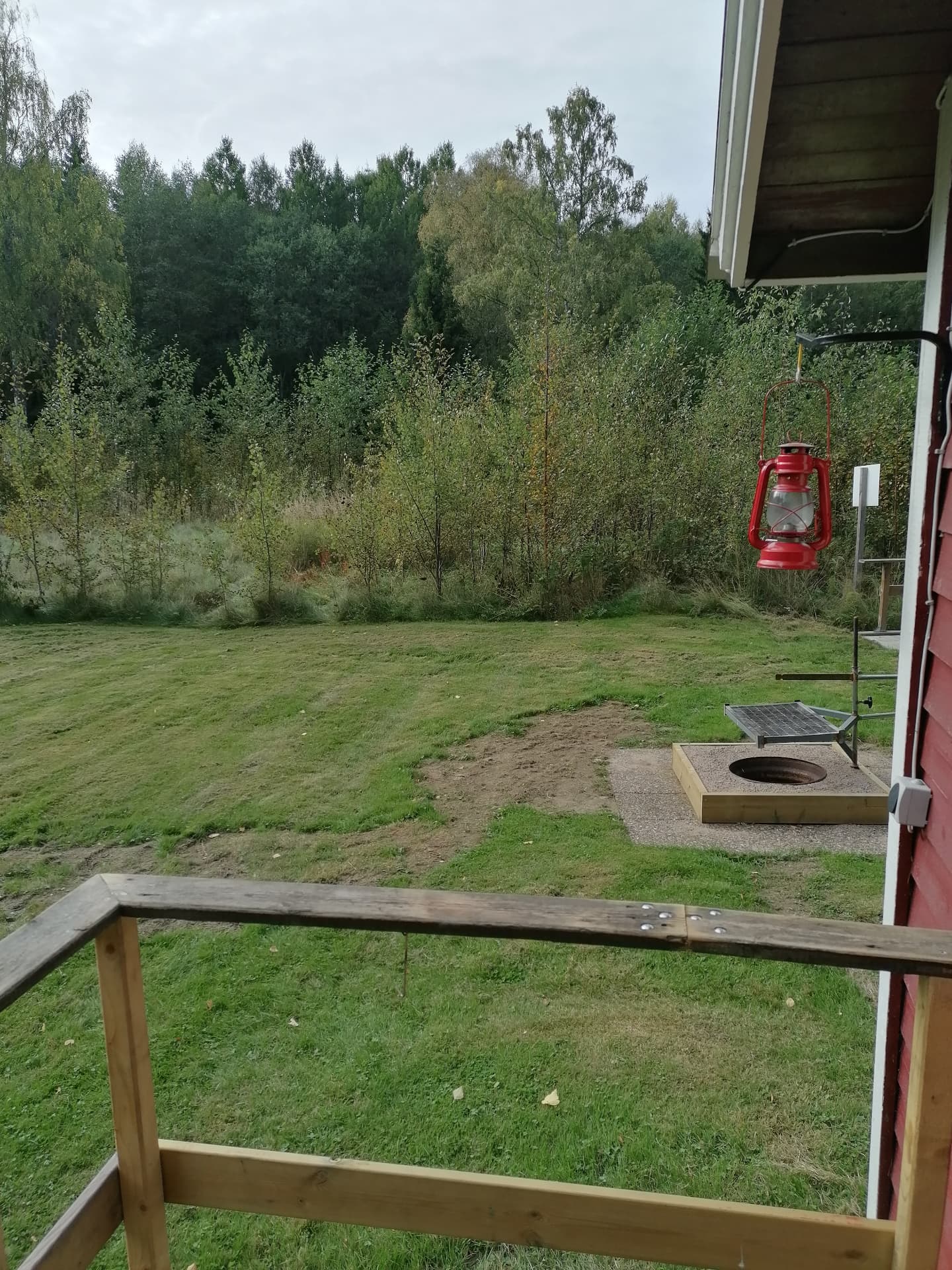 Kvällsljus över eldplatsen och trädgården vid stugan